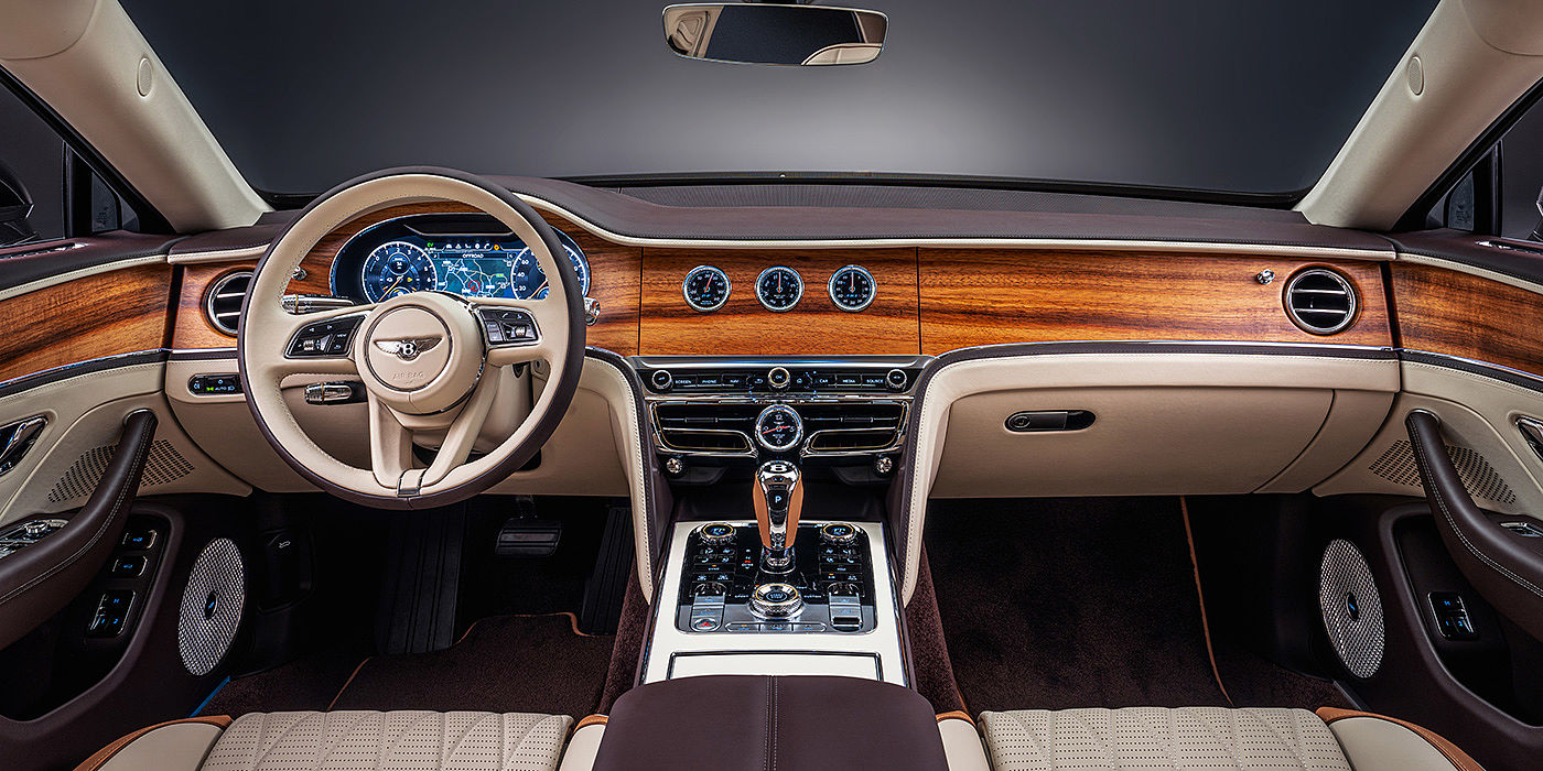 Bentley Doha Bentley Flying Spur Odyssean sedan front interior in Open Pore Koa veneer with Piano Linen console and Linen and Burnt Oak hides