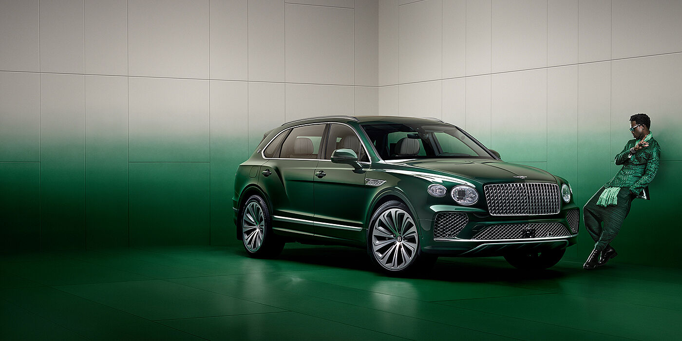 Bentley Doha Wisdom K leans against wall next to Bentley Bentayga Extended Wheelbase Atelier Edition SUV in Light Emerald green paint
