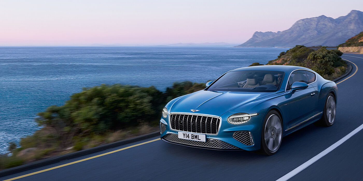 Bentley Doha New Bentley Continental GT Azure coupe in Light Windsor blue paint with 22 inch Azure wheels and chrome grill, driving dynamically by the se