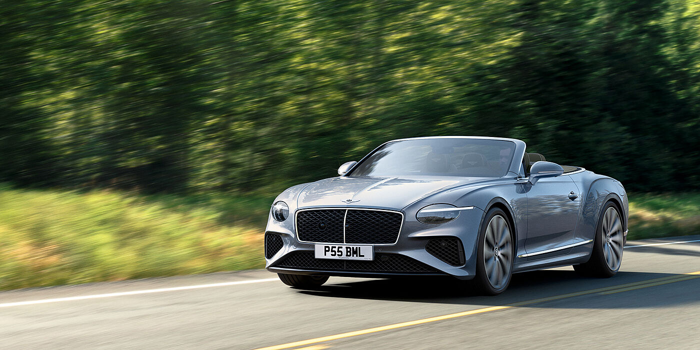 Bentley Doha New Bentley Continental GTC convertible front view in Silverlake paint with 22 inch ten spoke wheels, driving dynamically on a country road
