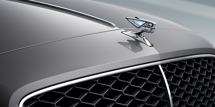Bentley Doha Bentley Flying Spur Speed sedan exterior close up in Tourmaline Green paint with chrome B wing vent, chrome Speed badge and 22 inch ten swept spoke wheel
